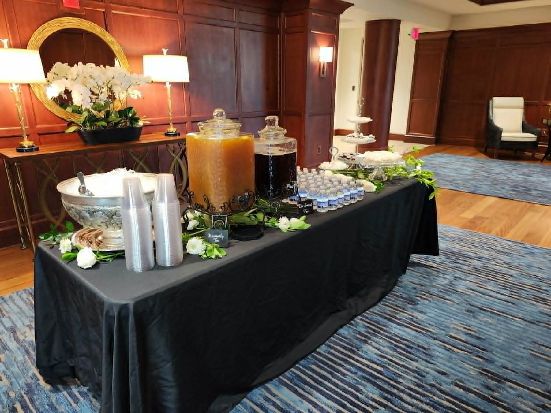 Elegant beverage station with tea, water, greenery, and black linens