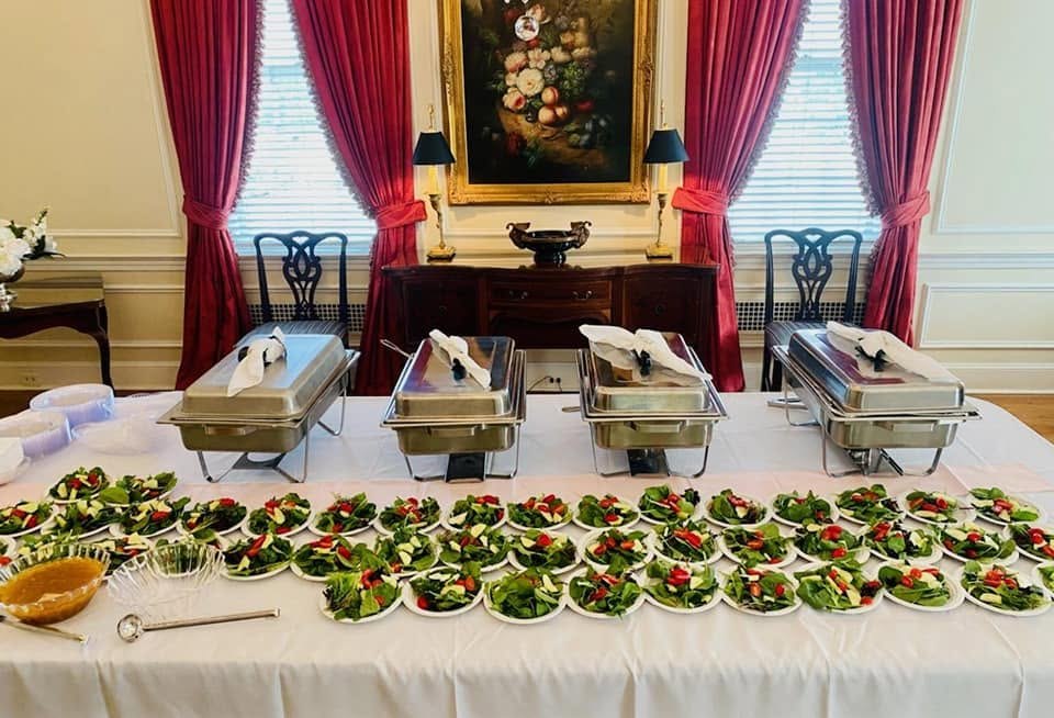 Formal buffet with rows of individual salads and chafing dishes