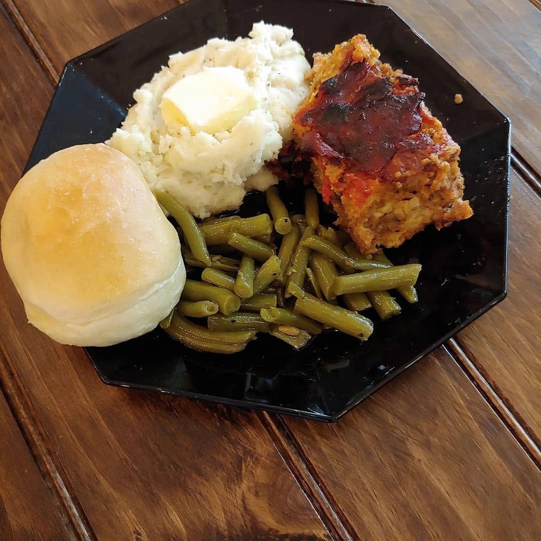 Comfort-food plate with meatloaf, mashed potatoes, green beans, and a roll