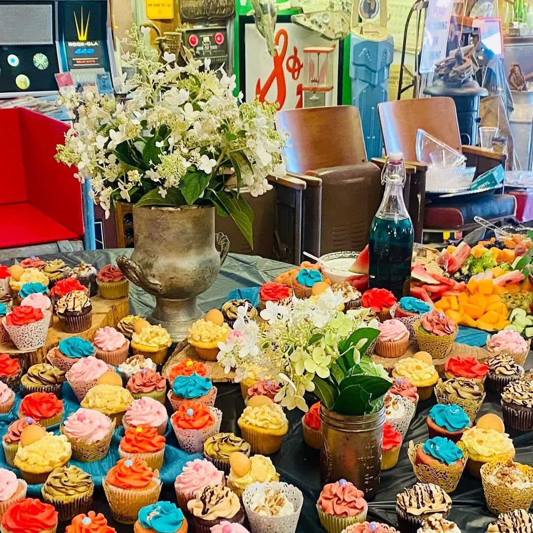 Colorful cupcake display beside fruit and grazing selections