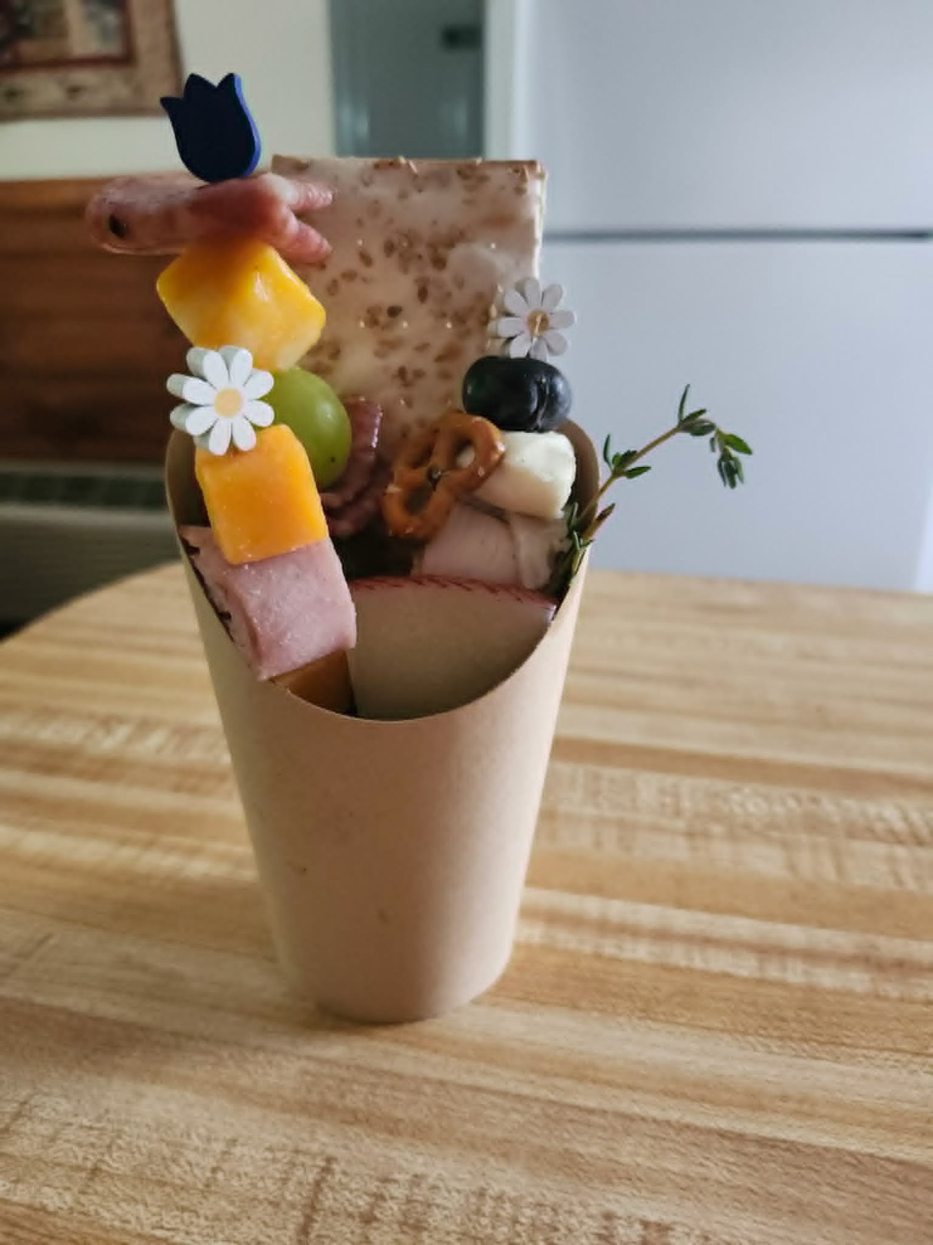 Individual grazing cup with meats, cheese, fruit, crackers, and herbs