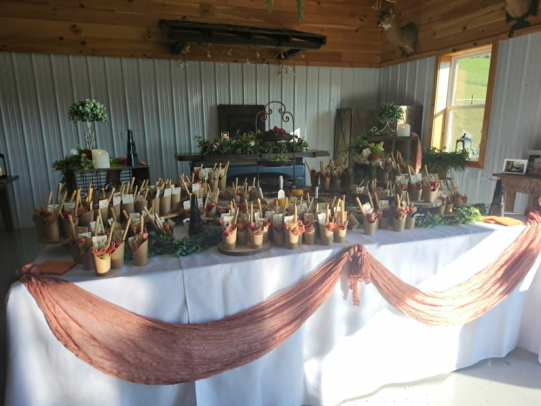 Long event table filled with individual appetizer cups and grazing selections