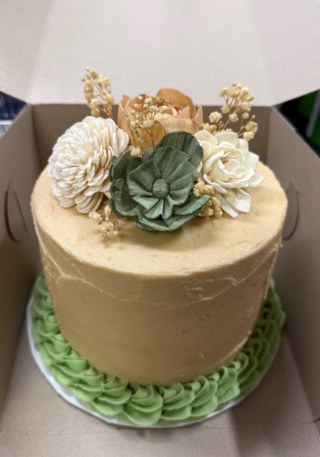 Neutral cake topped with sage green and ivory botanical flowers