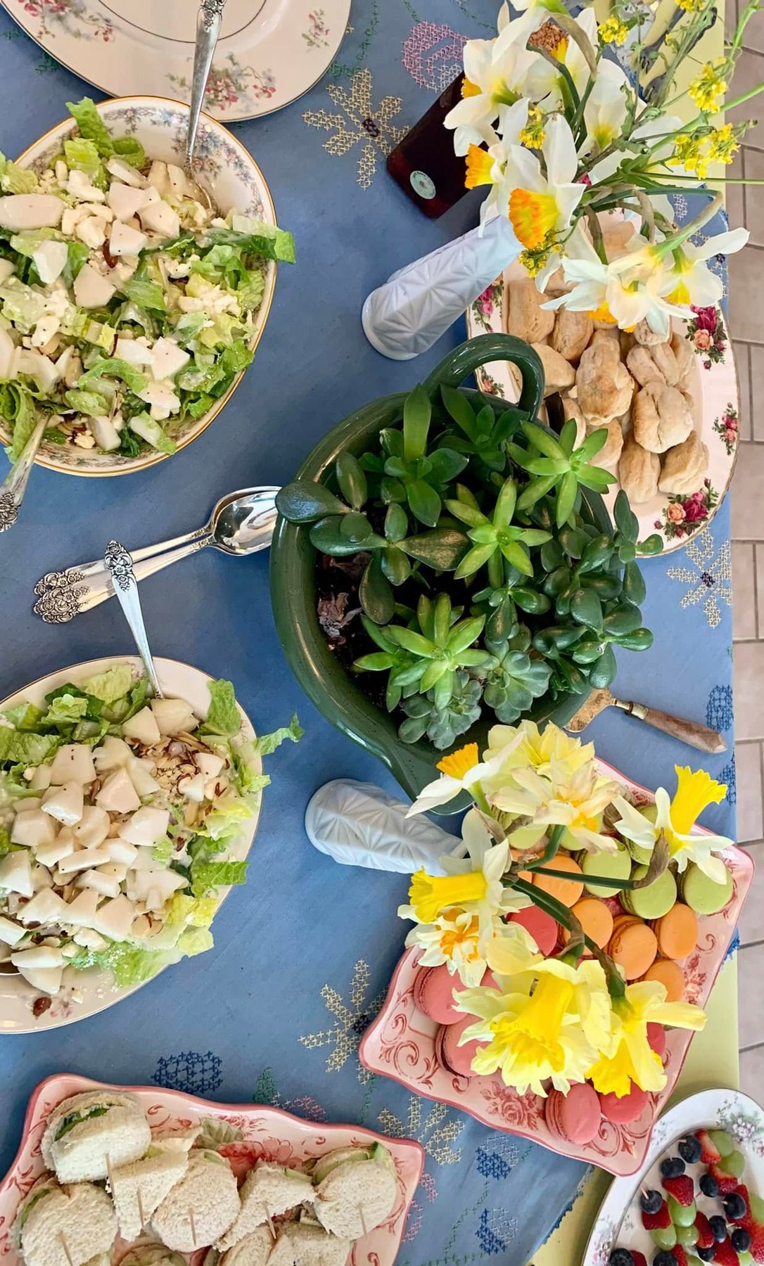 Tea luncheon table with salads, sandwiches, macarons, flowers, and china