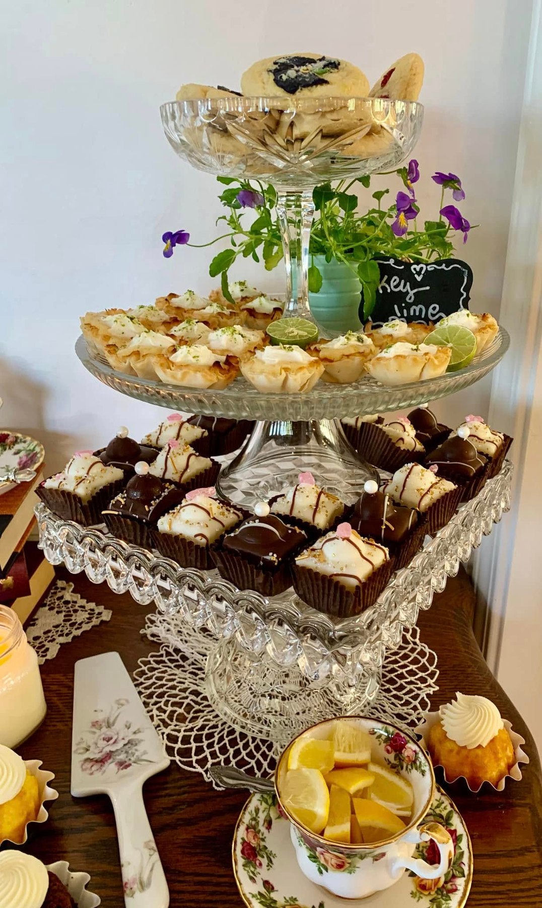 Tiered tea display with cookies, key lime bites, chocolate sweets, and lemon tea
