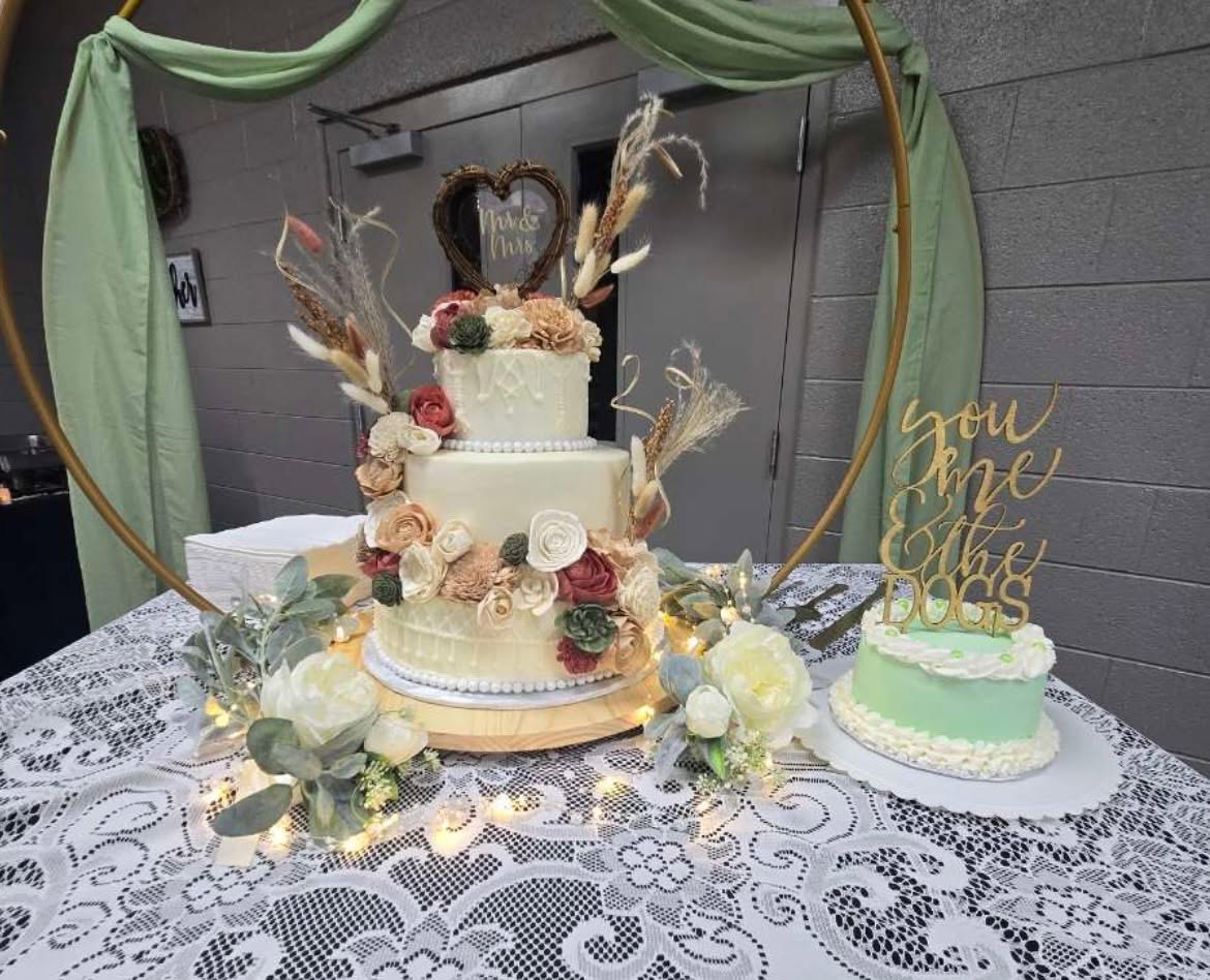 Three-tier floral wedding cake displayed with a coordinating smaller cake