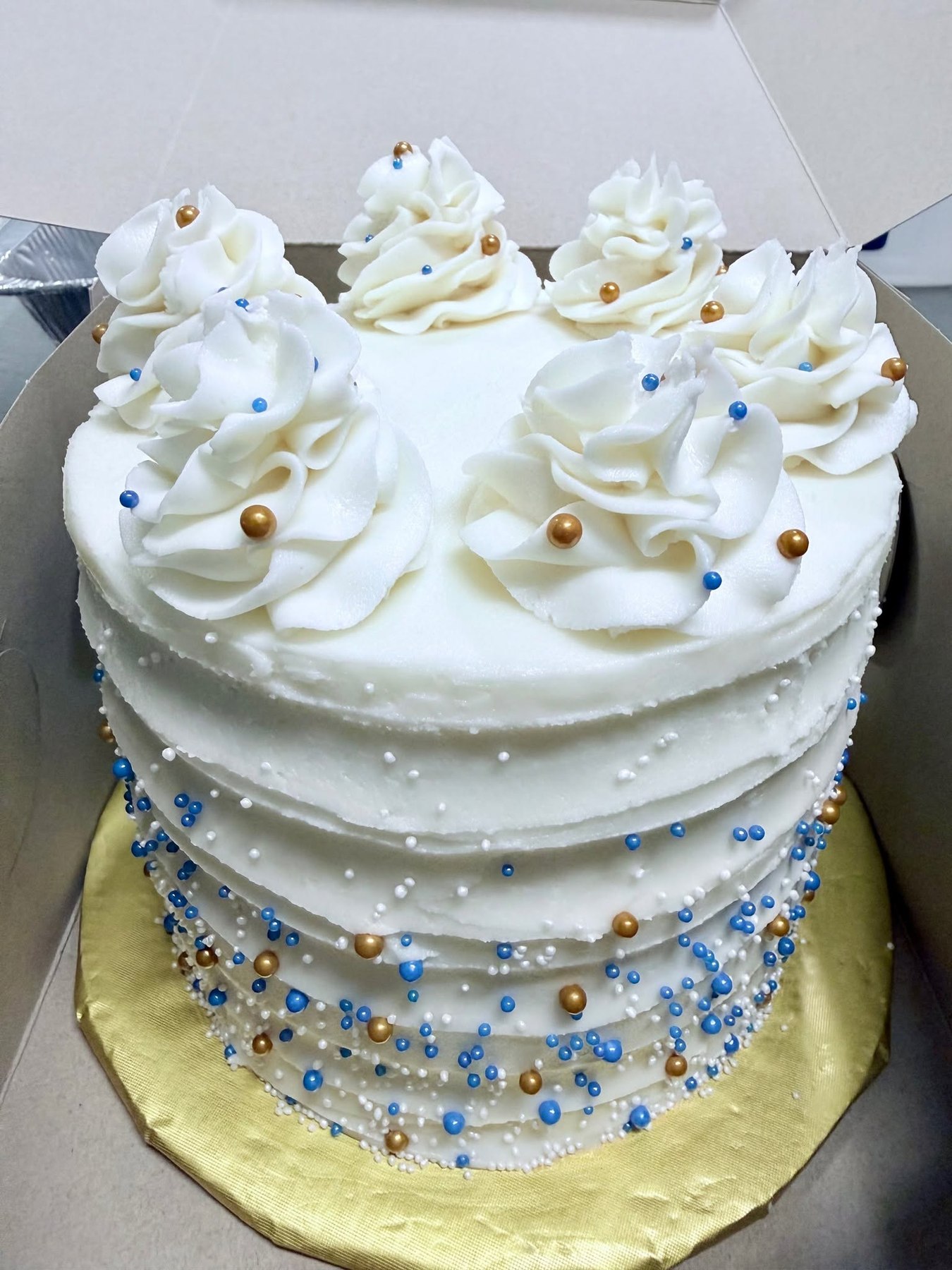 White celebration cake with blue and gold pearl details